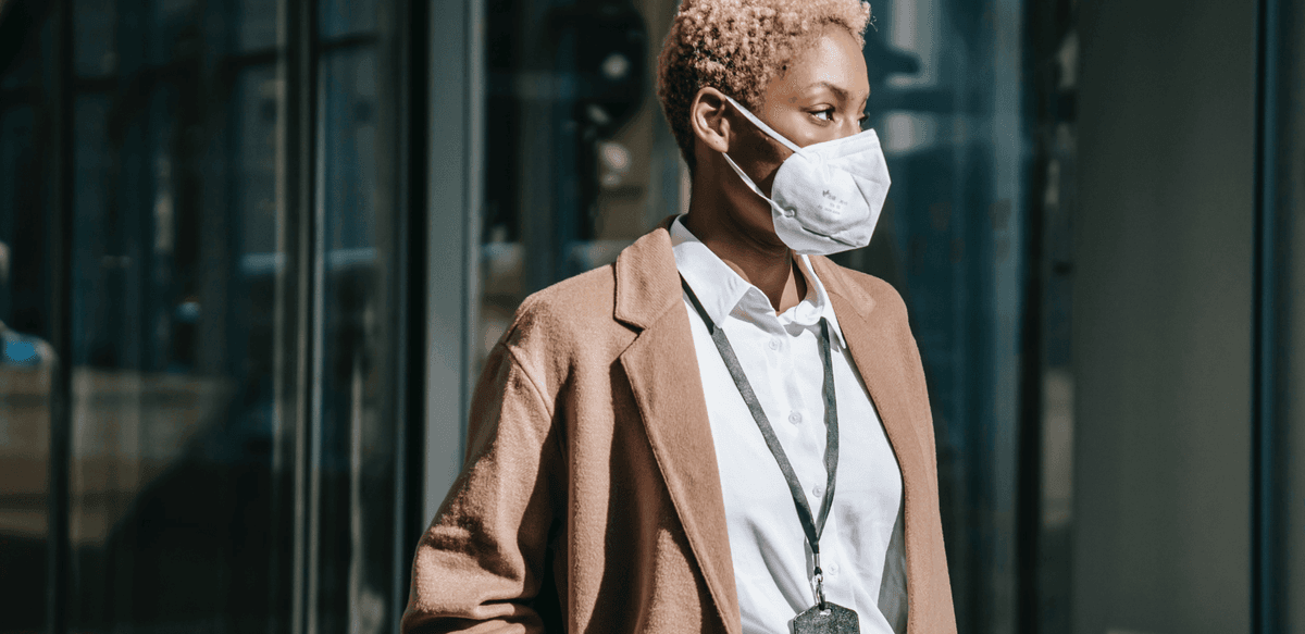 Frau trägt im Freien eine weiße medizinische Maske in einer Stadtszene